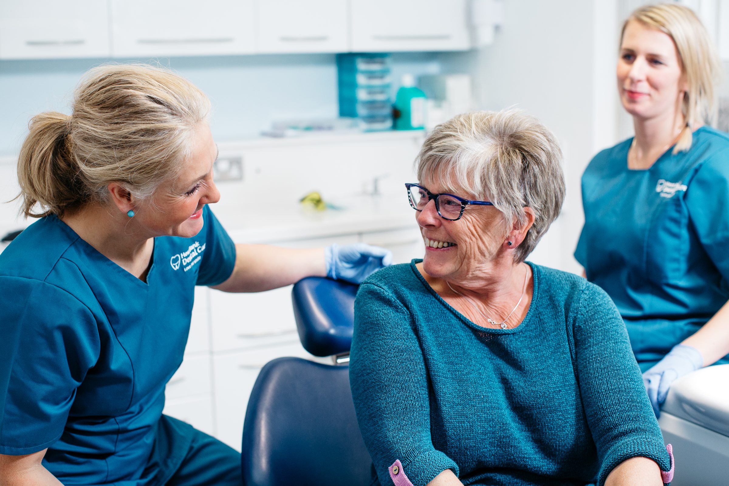 Dental team chatting with a smiling patient in the chair at Hest Bank Dental Care